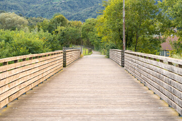 Small walkway pedestrian wooden bridge through the river in park