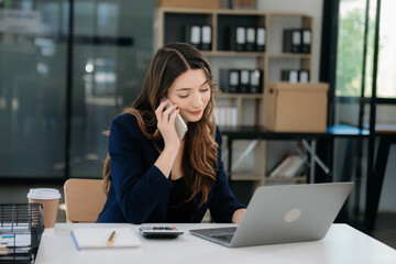 ung beautiful woman typing on tablet and laptop while sitting at the working white table