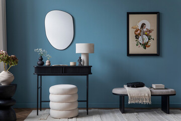 Cozy living room interior with mock up poster frame, white pouf, blue wall, black console, stylish lamp, vase with flowers, wooden stand, bench and personal accessories. Home decor. Template.	