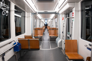 Empty public transportation tram car. Inside shot, nighttime, no people, empty seats