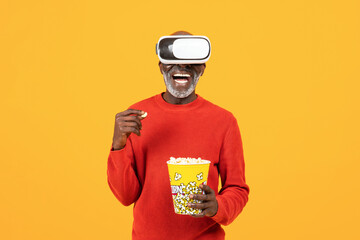 Smiling inspired senior african american man in vr 3d glasses, eat popcorn, watch film