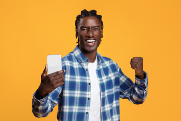 Online Win. Happy Young Black Guy Holding Smartphone And Celebrating Success