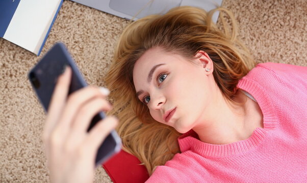 young beautiful woman have a rest lie on the floor hold smartphone in arms nice holiday concept voip telephony