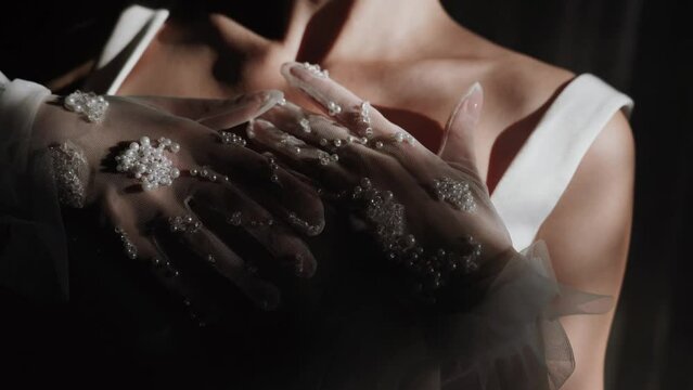 Stylish woman model in white gloves posing near a window in the sun. Portrait of a model in the shade. Fashion shooting concept 4k