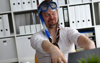 Man wearing suit and tie in goggles and snorkel articulate at workplace in office portrait. Count...