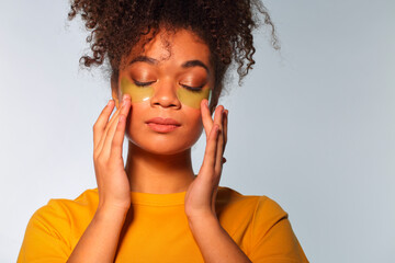 Skincare. Young african american woman applying hydrogel cosmetic eye patches to under-eye area