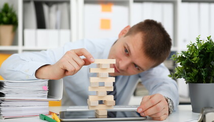 Businessman plays in strategy hand rearranging wooden blocks involved during break at work in...