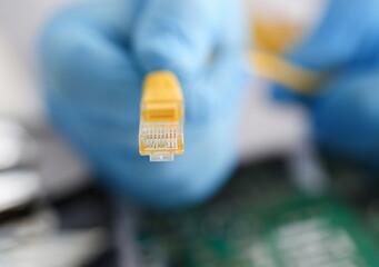 A male hand in blue protective gloves holds a network connector. The LAN constructor deconstructs...