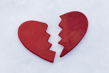 Red broken in half toy heart in the snow, concept or metaphor broken heart, background for...