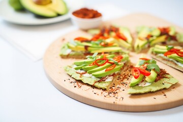 sliced avocado topping on a raw vegan pizza, with chili flakes
