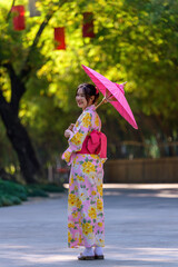 A young woman wearing a Japanese traditional kimono or yukata holding an umbrella is happy and...