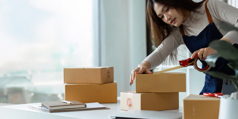 Young business entrepreneur sealing a box with tape. Preparing for shipping, Packing, online...