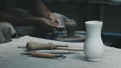 The sculptor at work. White Vase on Table. Potter's tools. Potter's hands on a Background. Filtered Photo