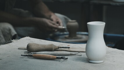 The sculptor at work. White Vase on Table. Potter's tools. Potter's hands on a Background. Filtered...