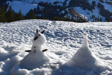 Frontal view of natural looking little snowbunny and snowman built by child with natural materials...