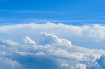 Fluffy white cumulus clouds in a blue sky on a beautiful day, natural soft background with copy...