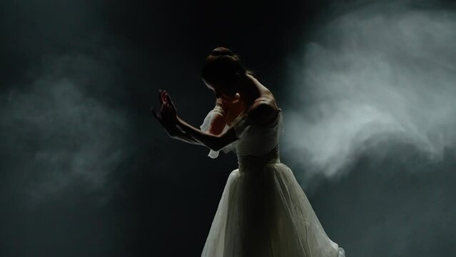 Performance, dramatic dance, graceful ballerina in a white tutu, perform choreographic elements on a black background, haze effect on a dark stage, super slow motion.