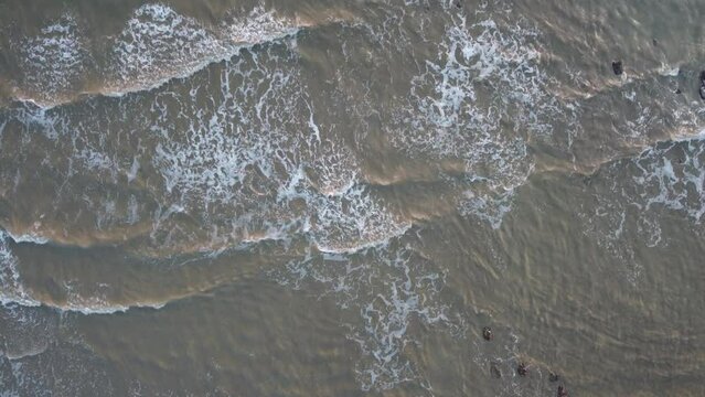 Waves lapping on the beach at sunset from a drone