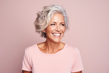 Beautiful senior woman. Portrait of a beautiful mature woman looking at camera and smiling while standing against pink background