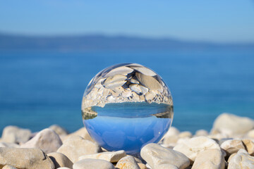 Glass ball lying on stones at the beach