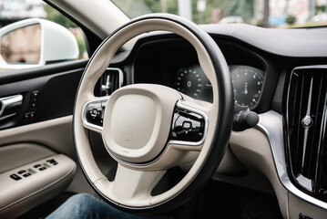 White and black luxury modern car interior. Steering wheel, speedometer, display, and multimedia...