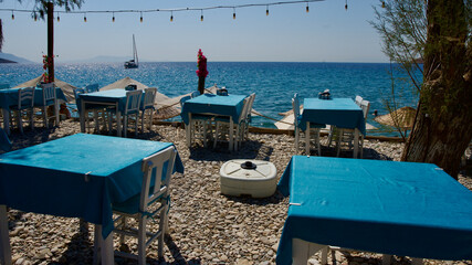 Fototapeta na wymiar Aegean and Mediterranean coasts at sunset. Wicker umbrellas and sun loungers. Beach restaurants. Palamutbuku beaches of Mugla, Turkiye.