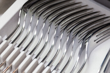 Silverware set background. Shiny silver forks in a row. Kitchen utensil background.
