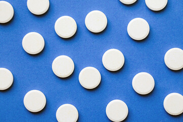 White round pills on blue. Vitamins to dissolve in water pattern. Soluble medicine texture.