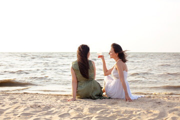 Fototapeta na wymiar Happy adult women with wine resting on beach