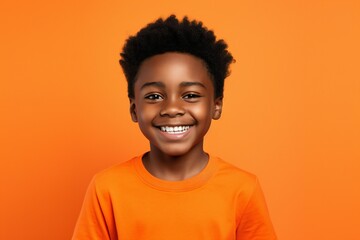 a professional portrait studio photo of a cute black boy child model with perfect clean teeth laughing and smiling. isolated on orange background. for ads and web design