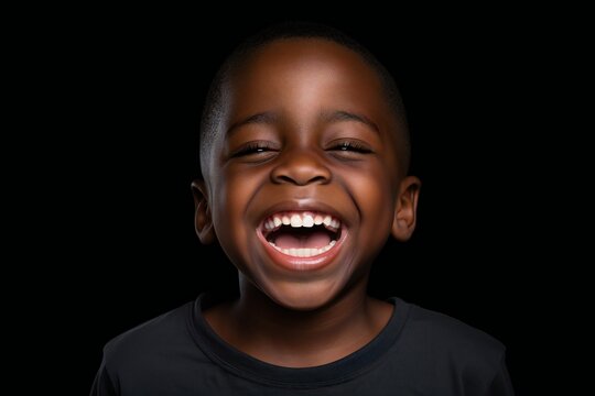 a professional portrait studio photo of a cute african boy child model with perfect clean teeth laughing and smiling. isolated on black background. for ads and web design