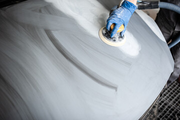 Car paint shop in a car service place. Close up photo of a male hand working to polish and paint...