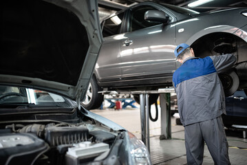 Tyres car service. Man working at a car to repair its parts at an auto vehicles service. Concept image for tyre cars maintenance.