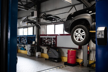 Tyres car service. Man working at a car to repair its parts at an auto vehicles service. Concept image for tyre cars maintenance.