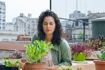 young latin woman working doing maintenance to plants on terrace