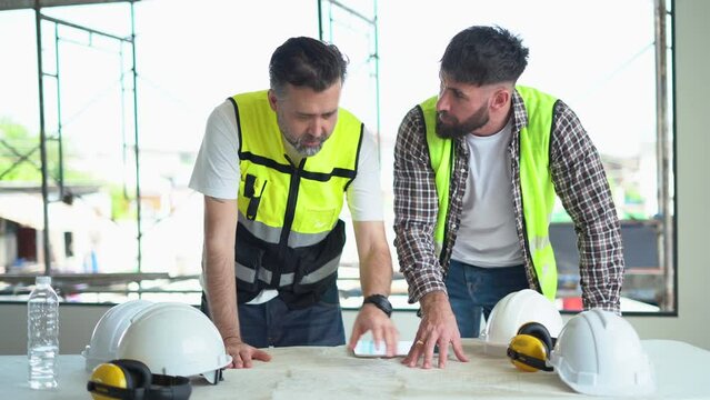 team of Construction workers Senior architect or civil engineer and foreman discussion to inspection structure apartment with blueprint at construction site. building project