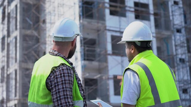team of Construction workers Senior architect or civil engineer and foreman walking and discussion to inspection or checking structure apartment with tablet  at construction site. building project