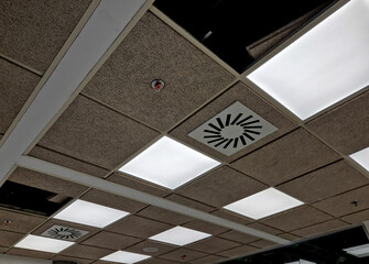 modular ceiling with soffit boards, lights that are connected from a ladder by an electrician worker. repair of the ceiling with an assembly hatch. air conditioning concealed under a double suspended 