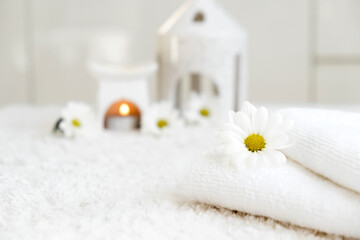 Obraz na płótnie Canvas White towels with chamomile flower and aroma lamp, candle. Spa and wellness or beauty salon, romantic relaxation concept. Copy space. Womens Day. Valentines Day.
