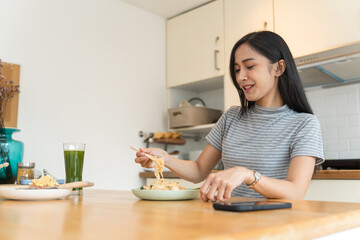 Asian Girl  eating Thai food in kitchen counter Home delivery food feeling happy 