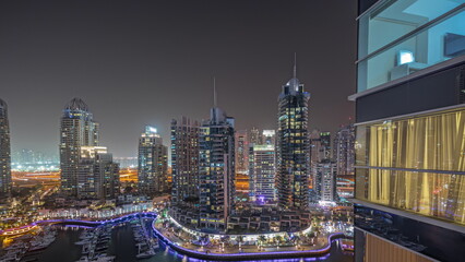 Fototapeta premium Panorama showing Dubai marina tallest skyscrapers and yachts in harbor aerial night timelapse.