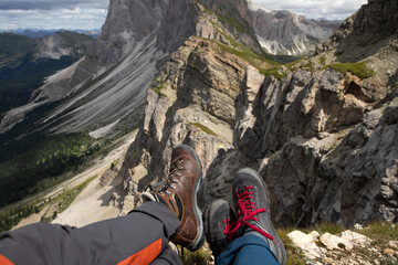 Trekking boots of a hiker couple while sitting on top of a mountain in Seceda, Dolomites, Italy