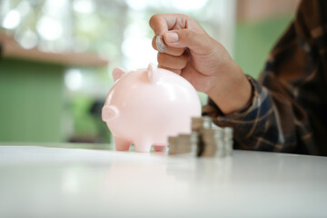 Saving money. hand putting money into pink piggy bank making investments or strategy for personal savings