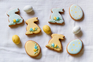 Easter homemade bake gingerbread with different pattern of icing for cookies in the shape of eggs and bunny. Easter eggs. White textile background, top view, copy space