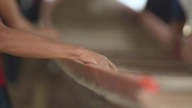 The hands of a shipbuilder are holding the hull of a boat