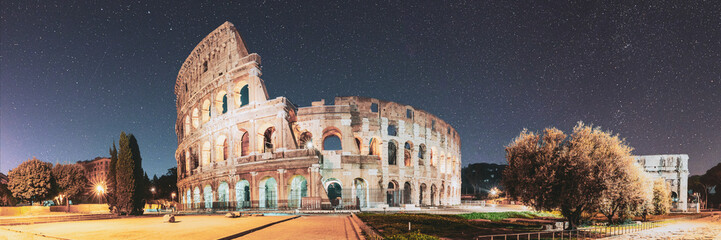 Rome, Italy. Colosseum Also Known As Flavian Amphitheatre In Evening Or Night Time. Bold Bright Blue Night Starry Sky With Glowing Stars Above Colosseum. Panoramic View. Travel To Italy.
