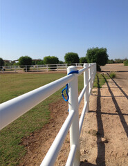 White rail fence on grass bank against blue sky