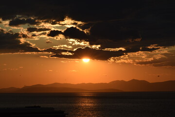 Dramatic Sunset Over the Ocean with Clouds and Mountains Silhouette