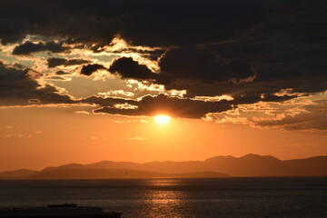 Dramatic Sunset Over the Ocean with Clouds and Mountains Silhouette