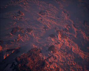 Aerial of rocky terrain covered in snow at sunset.
